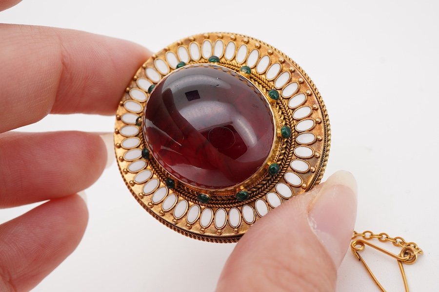 A garnet brooch, second half 19th century, designed in the Archaeological Revival style, centring on a large foiled cabochon garnet measuring approximately 25 x 21mm, within a border applied with rope twist decoration an